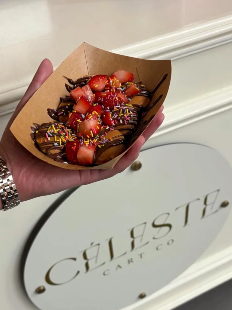 A tray of mini pancakes with strawberries held up at the cart