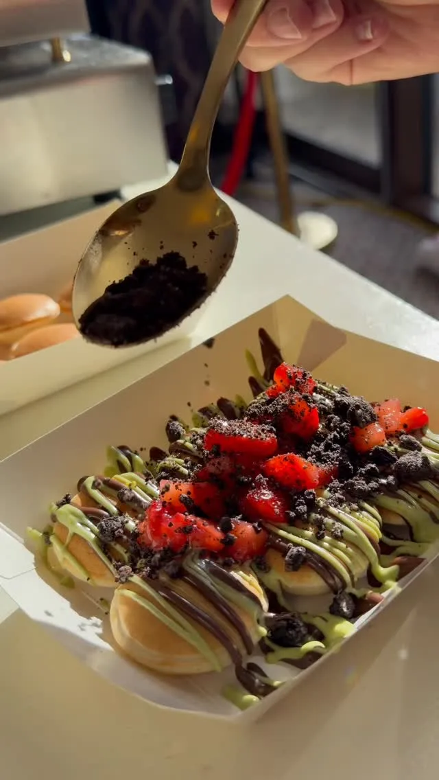 Toppings spooned over mini pancakes with strawberries